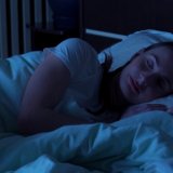 Young woman comfortably sleeping at night in a bed at home.